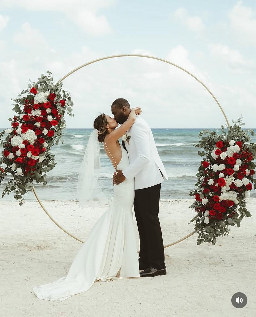 Beach ceremony first kiss under floral arch